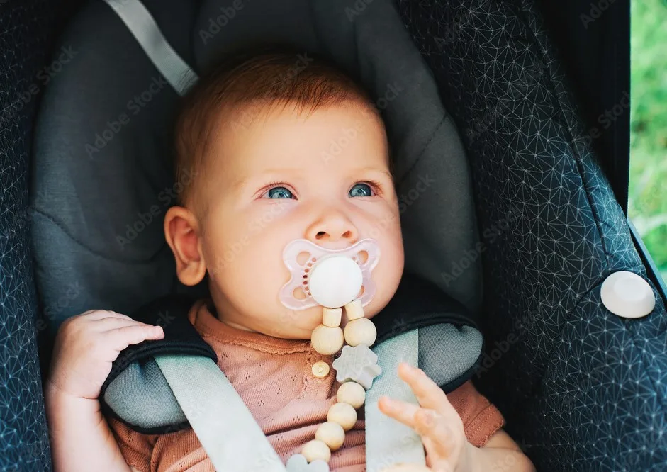 Baby with Personalized Pacifier Clips sitting quietly in Pram